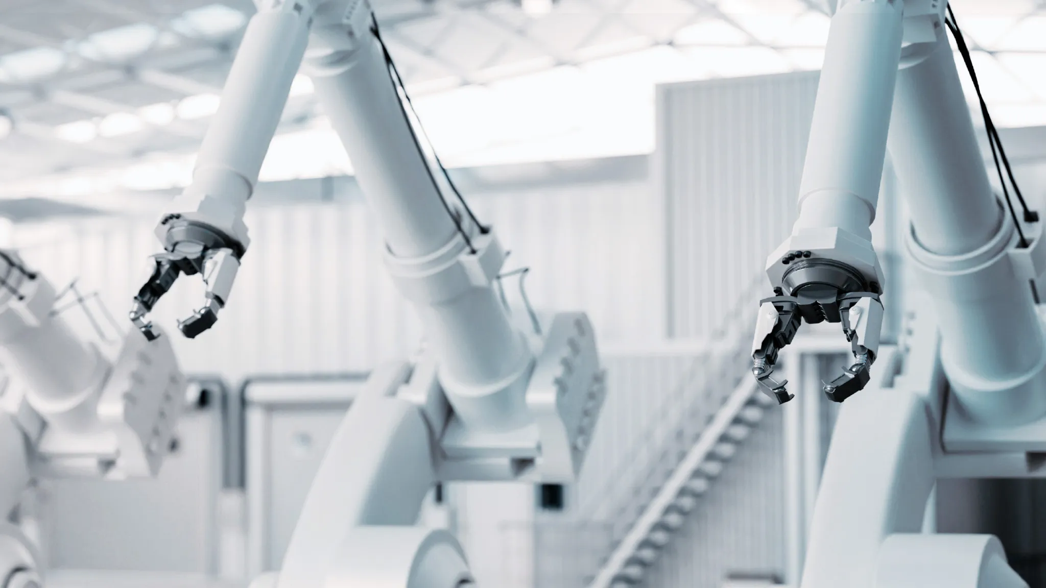 WHITE ROBOT ARMS IN A WHITE INDUSTRIAL HALL.