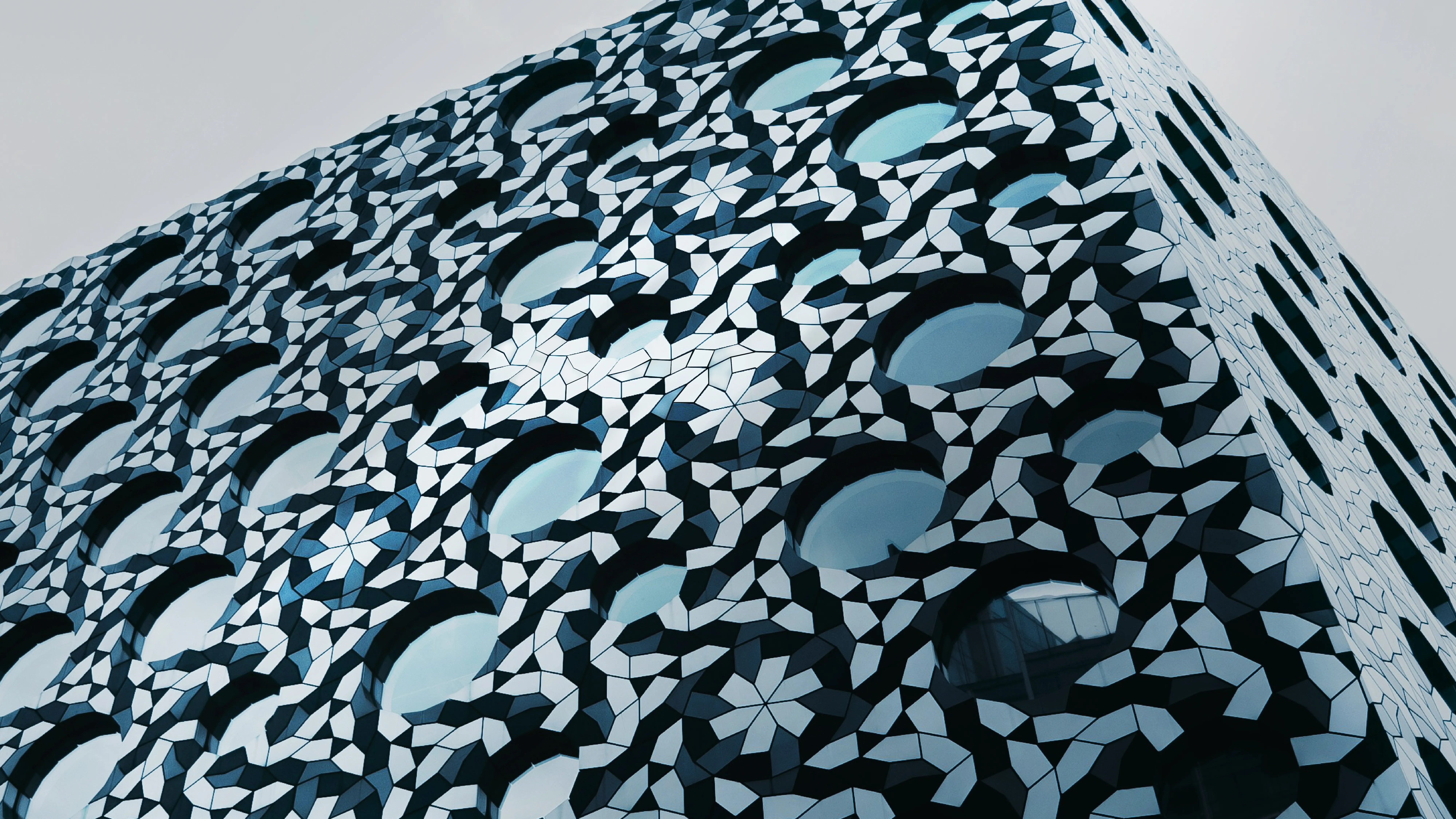 CORNER OF THE BUILDING WITH ABSTRACT MOSAIC FACADE AND ROUND WINDOWS.